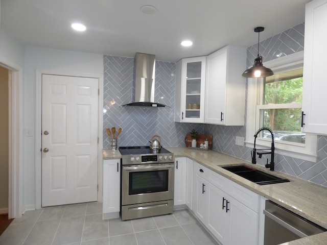 kitchen featuring stainless steel appliances, wall chimney range hood, sink, pendant lighting, and backsplash