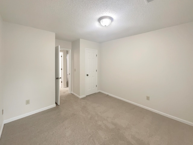 unfurnished room with a textured ceiling and light carpet