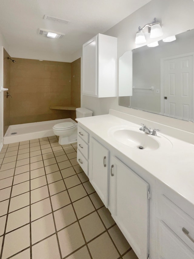 bathroom with vanity, tile patterned floors, toilet, and tiled shower