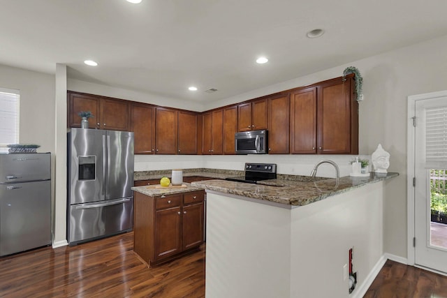 kitchen featuring appliances with stainless steel finishes, dark stone countertops, kitchen peninsula, and dark hardwood / wood-style floors