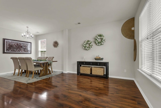 dining space featuring dark hardwood / wood-style flooring and an inviting chandelier