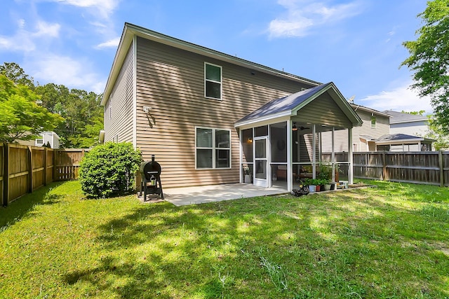 rear view of house with a sunroom, a patio, and a lawn