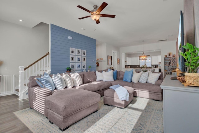 living room featuring ceiling fan, wood walls, and light hardwood / wood-style flooring