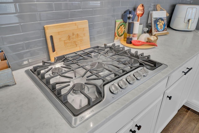 details featuring stainless steel gas stovetop, white cabinetry, and dark wood-type flooring