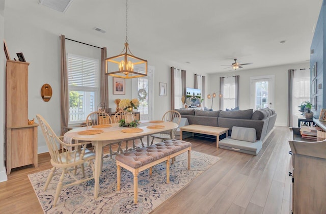 dining room featuring ceiling fan with notable chandelier and light hardwood / wood-style floors