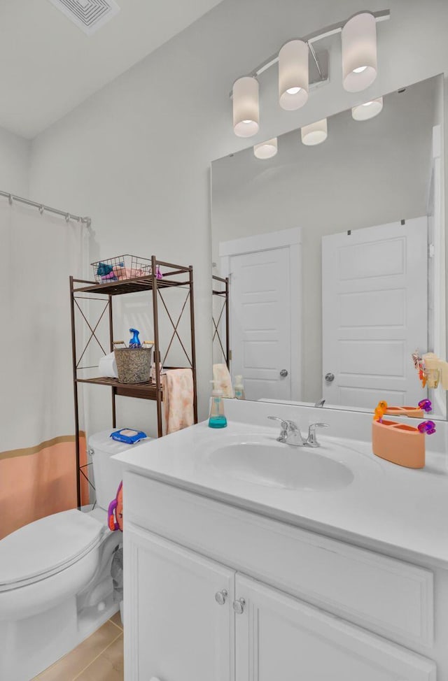 bathroom featuring tile patterned flooring, vanity, toilet, and walk in shower