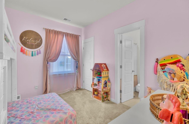 bedroom with ensuite bathroom and light colored carpet