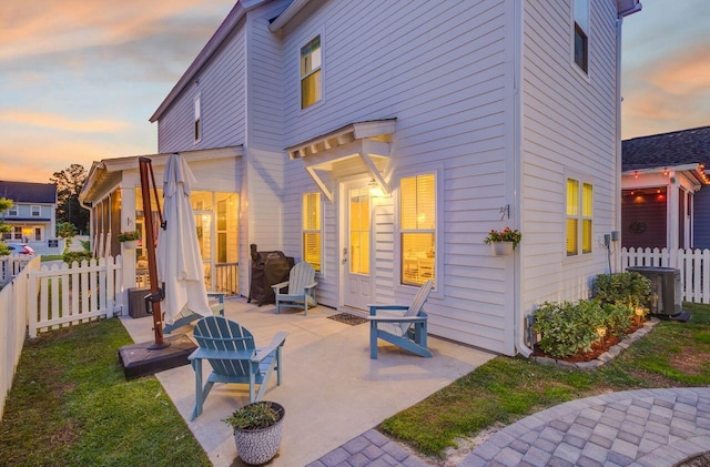 back house at dusk featuring a patio and central AC unit