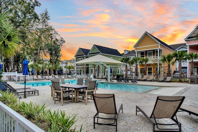 pool at dusk featuring a patio