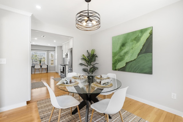 dining room with a notable chandelier, recessed lighting, light wood-type flooring, and baseboards