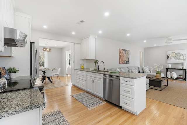 kitchen with visible vents, dishwasher, white cabinets, wall chimney exhaust hood, and a sink