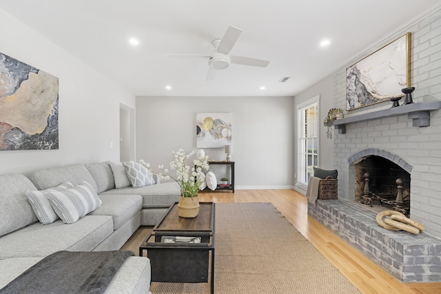 living room featuring wood finished floors, recessed lighting, a fireplace, and visible vents