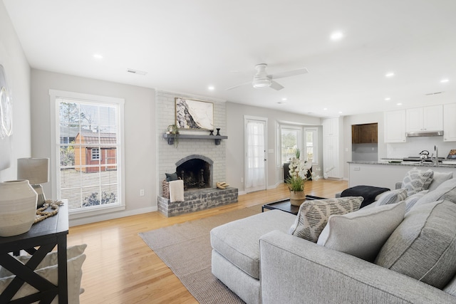 living room featuring recessed lighting, light wood-type flooring, baseboards, and a fireplace