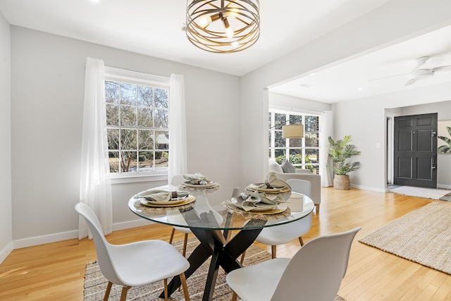 dining space featuring a wealth of natural light, ceiling fan with notable chandelier, baseboards, and light wood-style floors