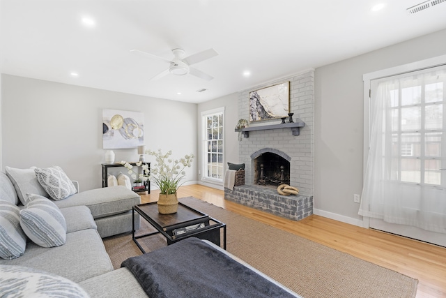 living room featuring a fireplace, recessed lighting, wood finished floors, and visible vents