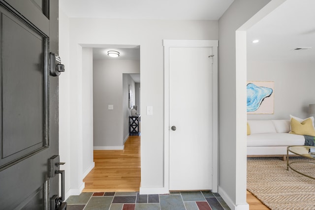 hall with visible vents, baseboards, and dark wood-type flooring