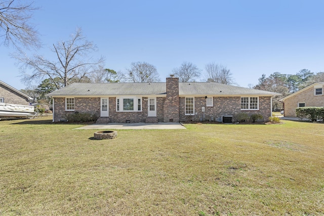 rear view of property with brick siding, a lawn, a chimney, crawl space, and a patio