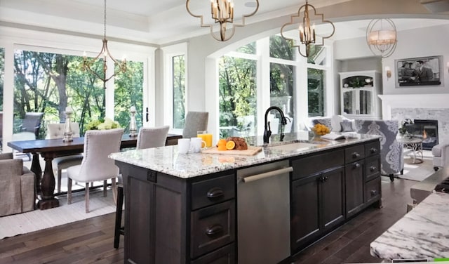 kitchen featuring a fireplace, pendant lighting, a chandelier, and stainless steel dishwasher