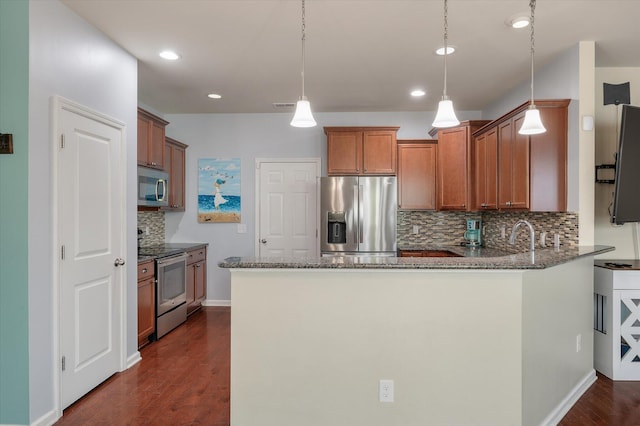 kitchen featuring a peninsula, dark wood-type flooring, stainless steel appliances, and dark stone countertops