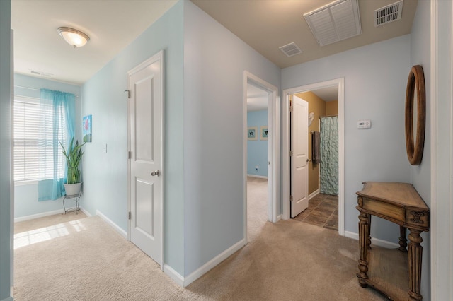 hallway with carpet floors, visible vents, and baseboards