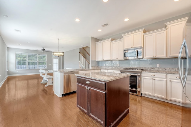 kitchen with stainless steel appliances, a center island, tasteful backsplash, light wood-type flooring, and recessed lighting