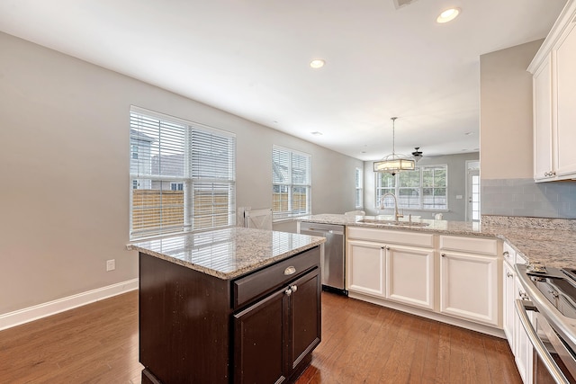 kitchen featuring dishwasher, a sink, range, a peninsula, and hardwood / wood-style floors