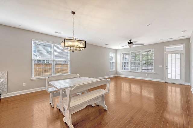 dining space featuring baseboards, wood finished floors, a chandelier, and a ceiling fan