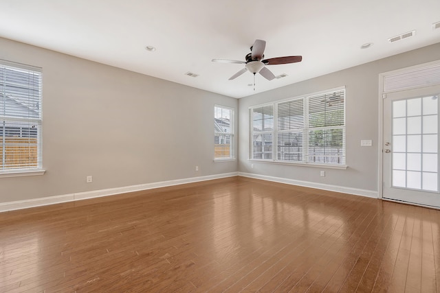 spare room featuring hardwood / wood-style flooring, a ceiling fan, and baseboards