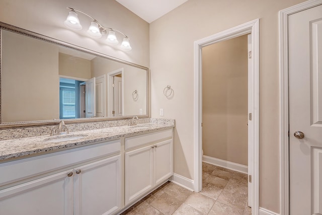 bathroom with double vanity and baseboards