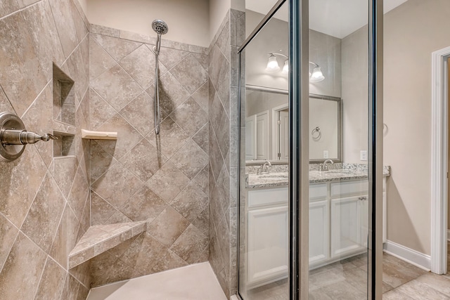 bathroom with a tile shower and double vanity