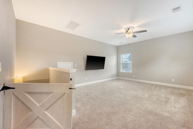 unfurnished living room with light colored carpet, a ceiling fan, and baseboards