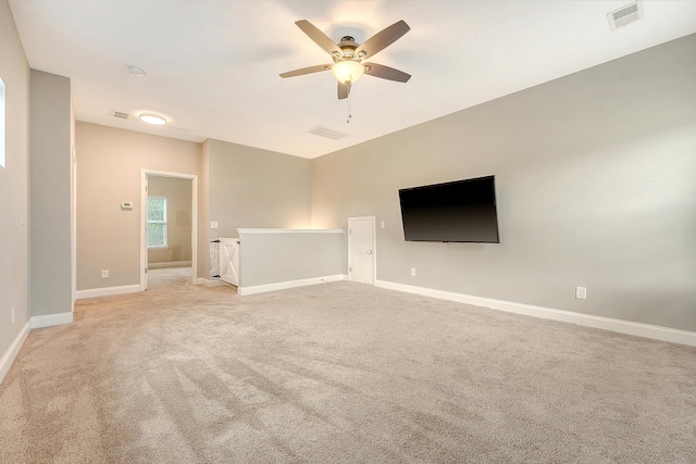 empty room with light carpet, a ceiling fan, and baseboards