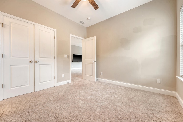 unfurnished bedroom with carpet floors, a closet, baseboards, and ceiling fan