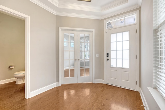 doorway with french doors, wood finished floors, ornamental molding, and baseboards