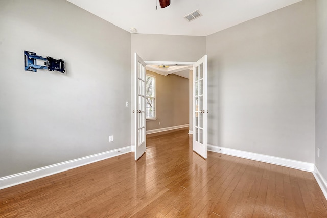 unfurnished room featuring french doors, baseboards, hardwood / wood-style floors, and a ceiling fan
