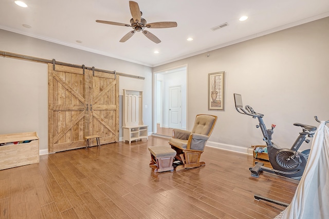 unfurnished room with a barn door, crown molding, ceiling fan, and wood-type flooring