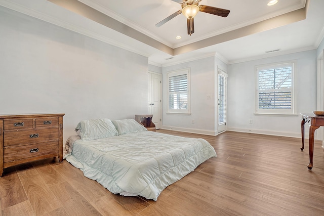 bedroom featuring ceiling fan, a raised ceiling, crown molding, and light hardwood / wood-style flooring