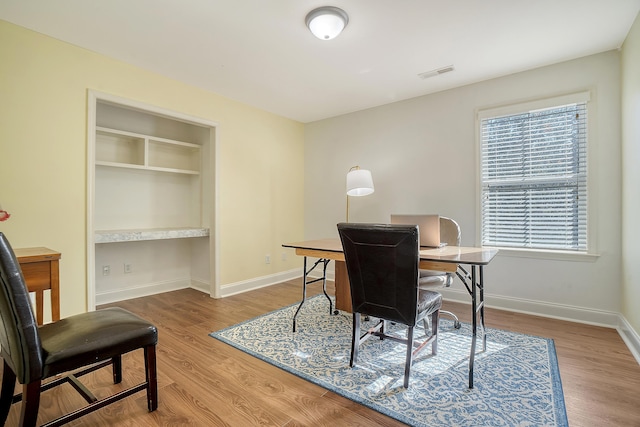 office area featuring wood-type flooring and built in features