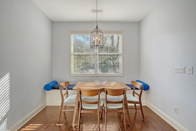 dining space with dark hardwood / wood-style floors and a notable chandelier