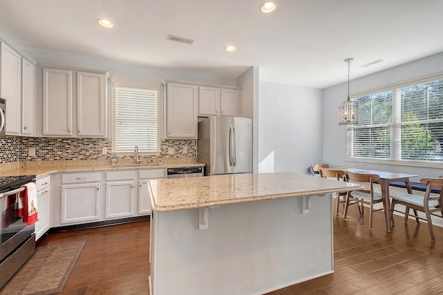 kitchen with white cabinets, a kitchen island, appliances with stainless steel finishes, and pendant lighting