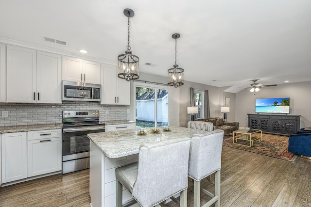 kitchen with wood finished floors, visible vents, white cabinets, appliances with stainless steel finishes, and backsplash