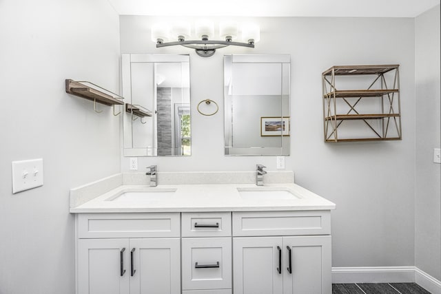 full bathroom with double vanity, baseboards, and a sink