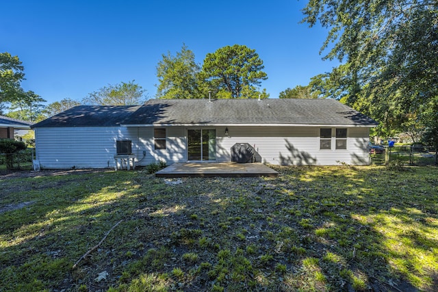 rear view of house featuring a wooden deck, fence, and a yard