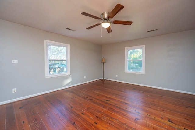 spare room with ceiling fan, a healthy amount of sunlight, and dark hardwood / wood-style flooring