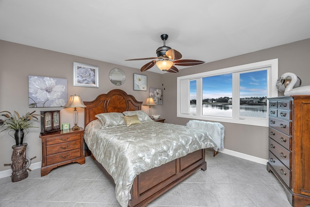 tiled bedroom featuring ceiling fan and a water view