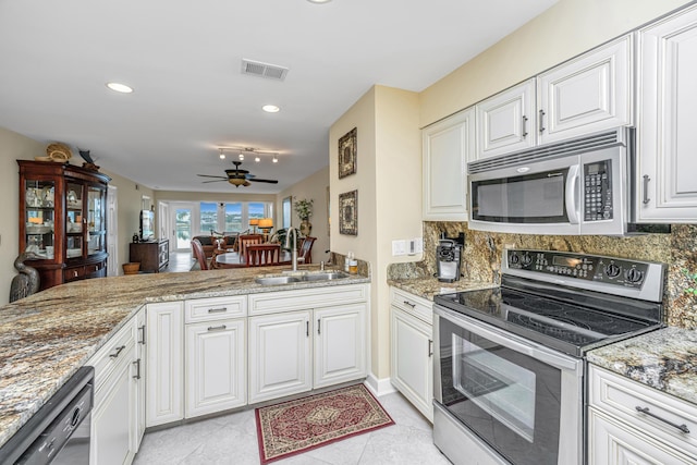 kitchen with stone counters, appliances with stainless steel finishes, tasteful backsplash, sink, and white cabinets