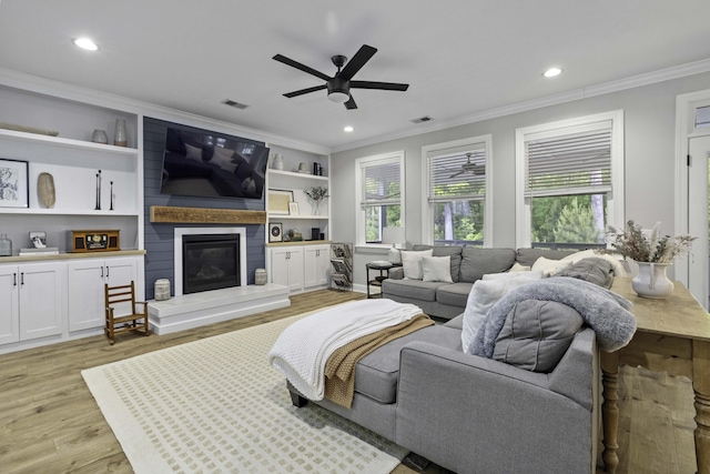 living area featuring visible vents, light wood-style flooring, crown molding, and ceiling fan