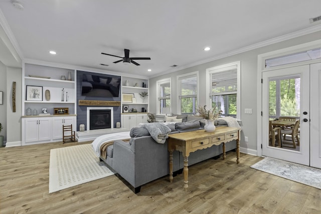 living room featuring ceiling fan, ornamental molding, a healthy amount of sunlight, and light wood-type flooring