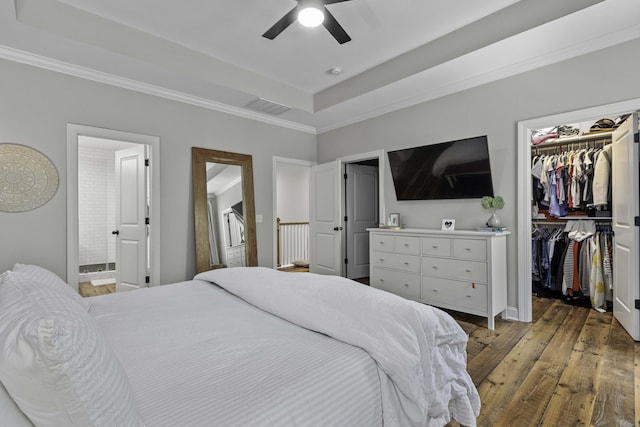 bedroom with hardwood / wood-style floors, a spacious closet, a tray ceiling, visible vents, and ornamental molding