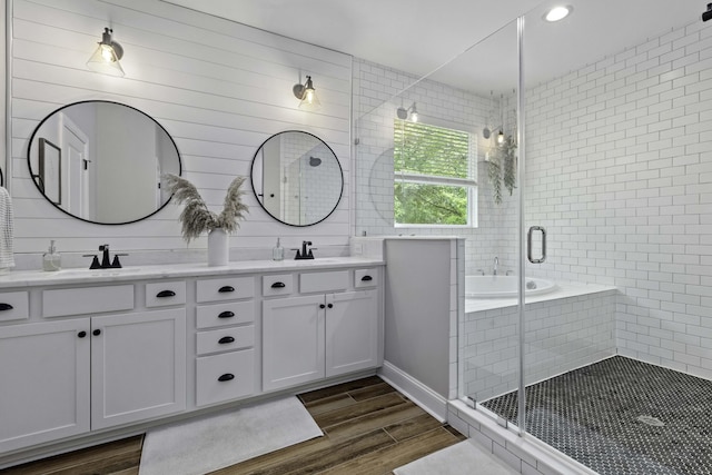 bathroom with a sink, double vanity, a shower stall, and wood finished floors